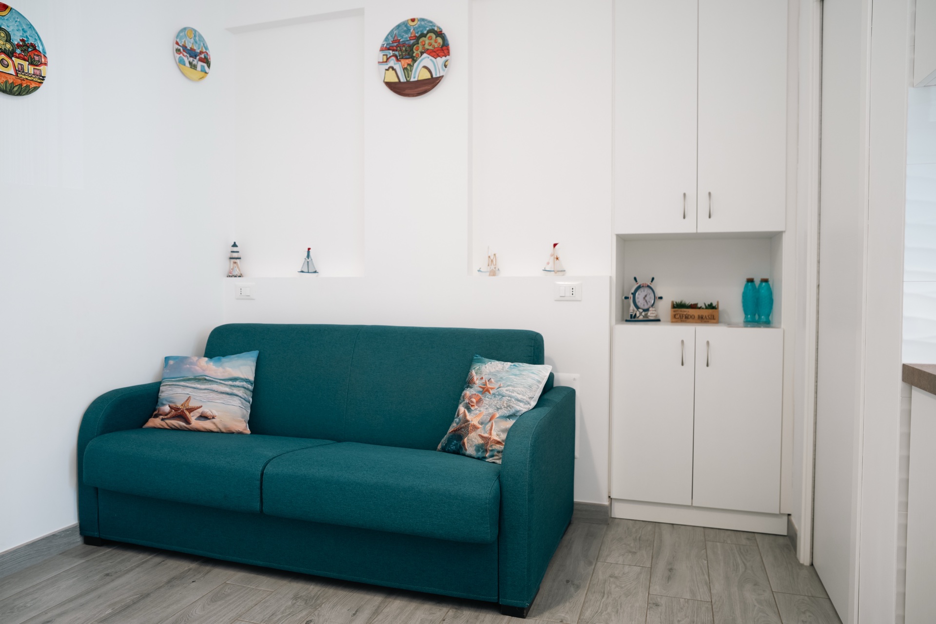 Casa Sofia, divano verde con piatti decorativi alle pareti