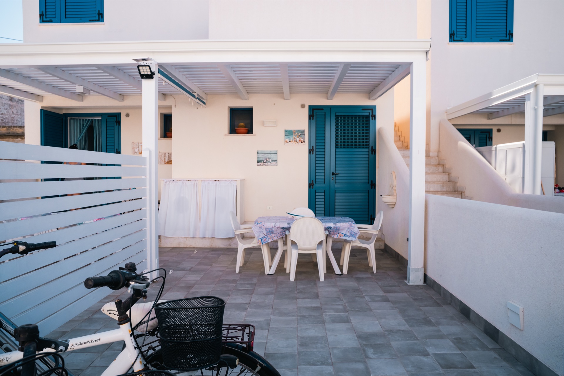 Patio con tavolo apparecchiato e bici sotto al pergolato