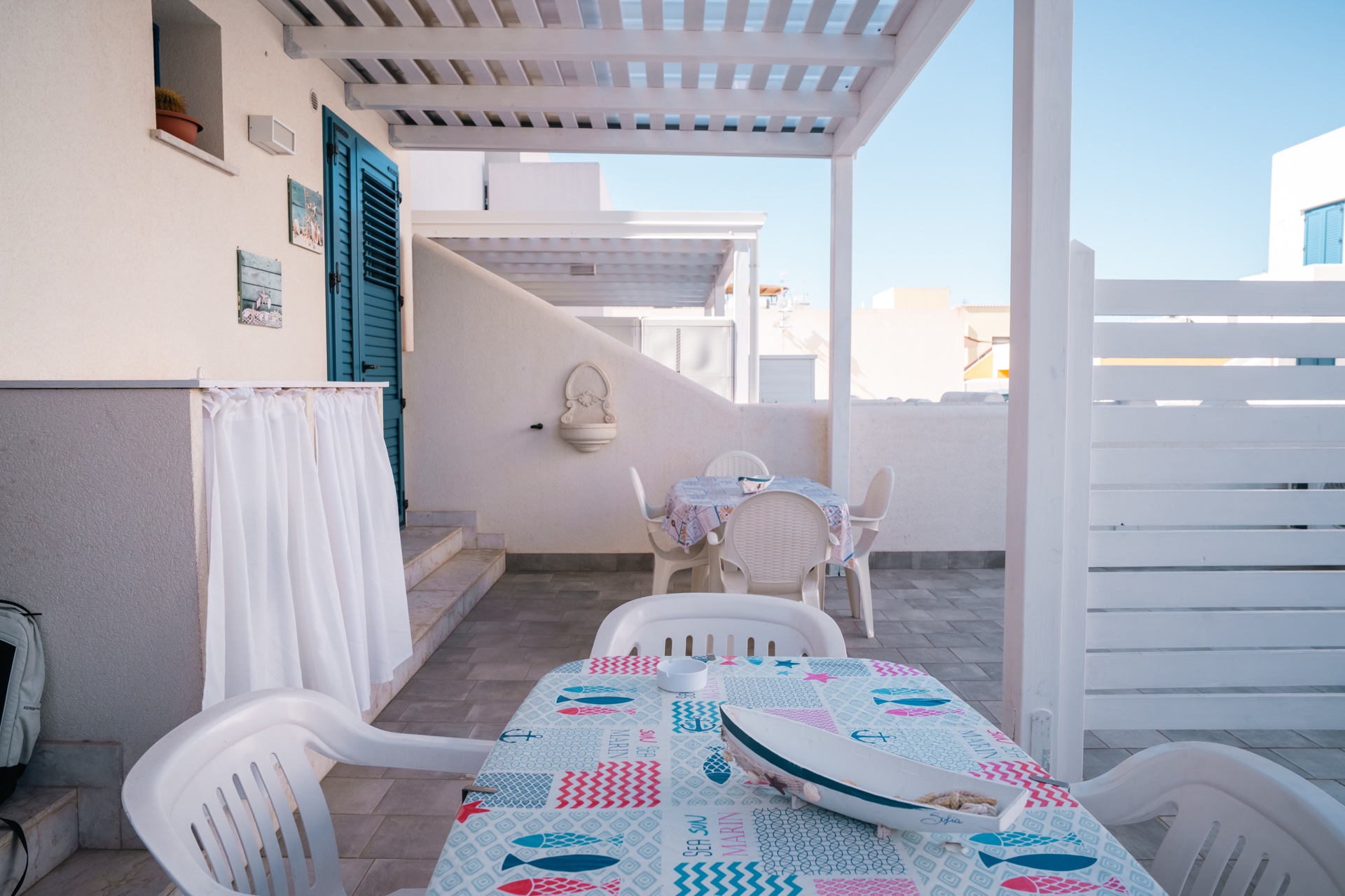 Veranda di Casa Sofia con tavolo, fontanella decorativa e barchetta