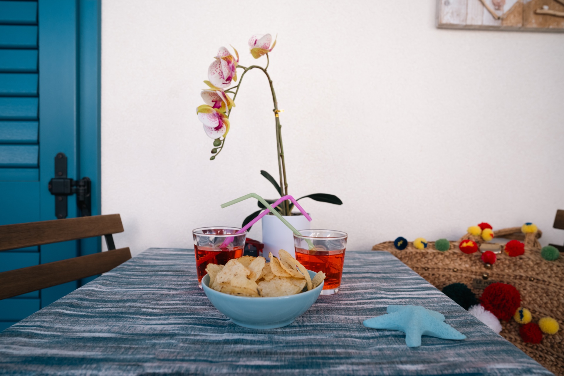 Dettaglio del tavolo con spritz, ciotola di patatine, orchidea e stella marina decorativa