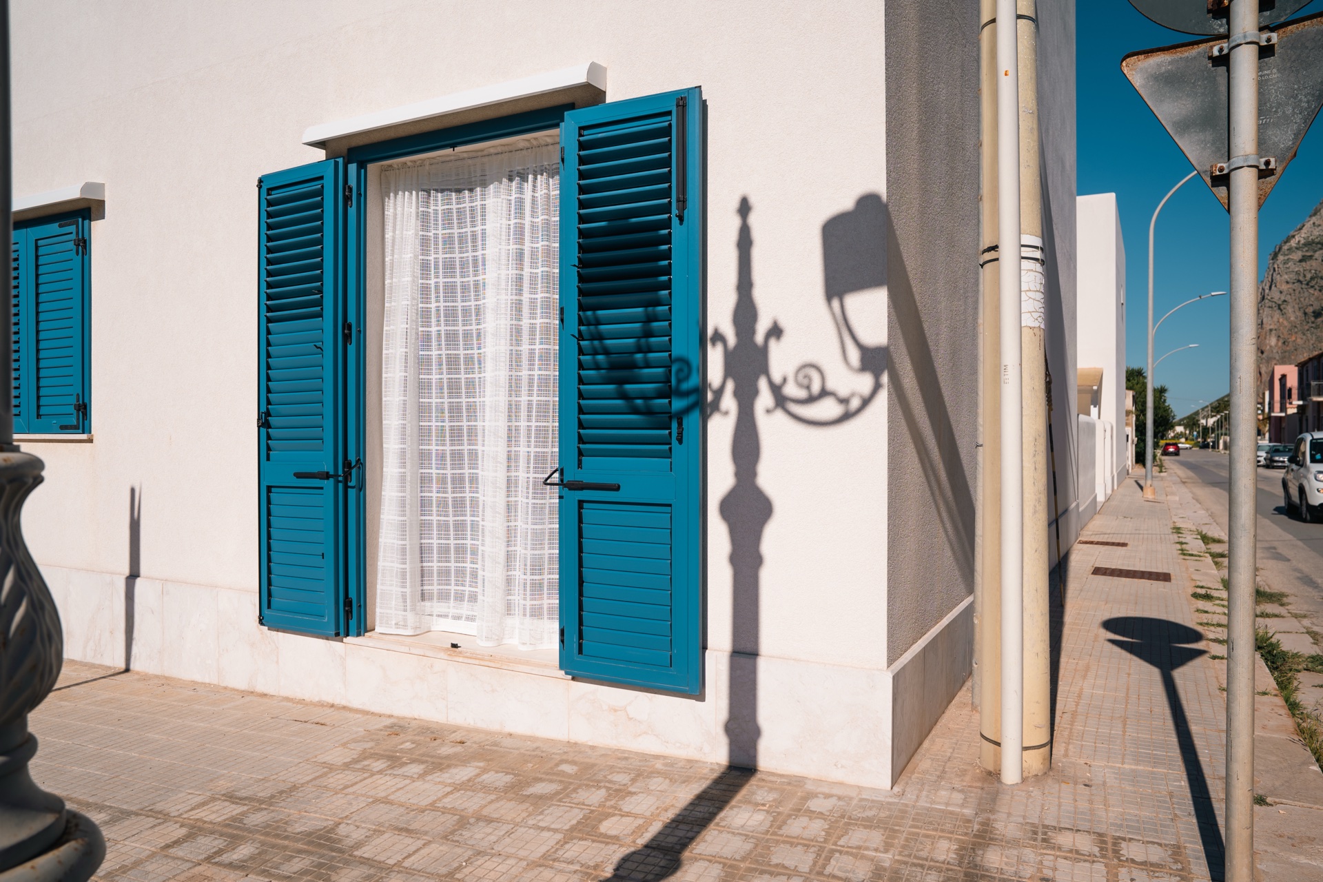 Finestra di Casa Asia con persiane azzurre, vista sulla strada di San Vito Lo Capo e il Monte Monaco in lontananza