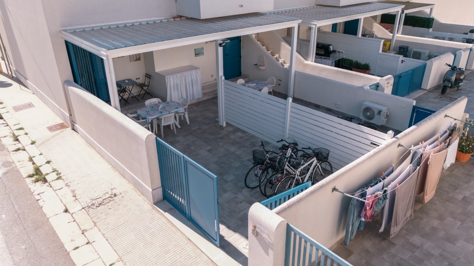 Vista dall'alto del cortile di Holiday Asia con bici, cancelli azzurri e due verande affiancate