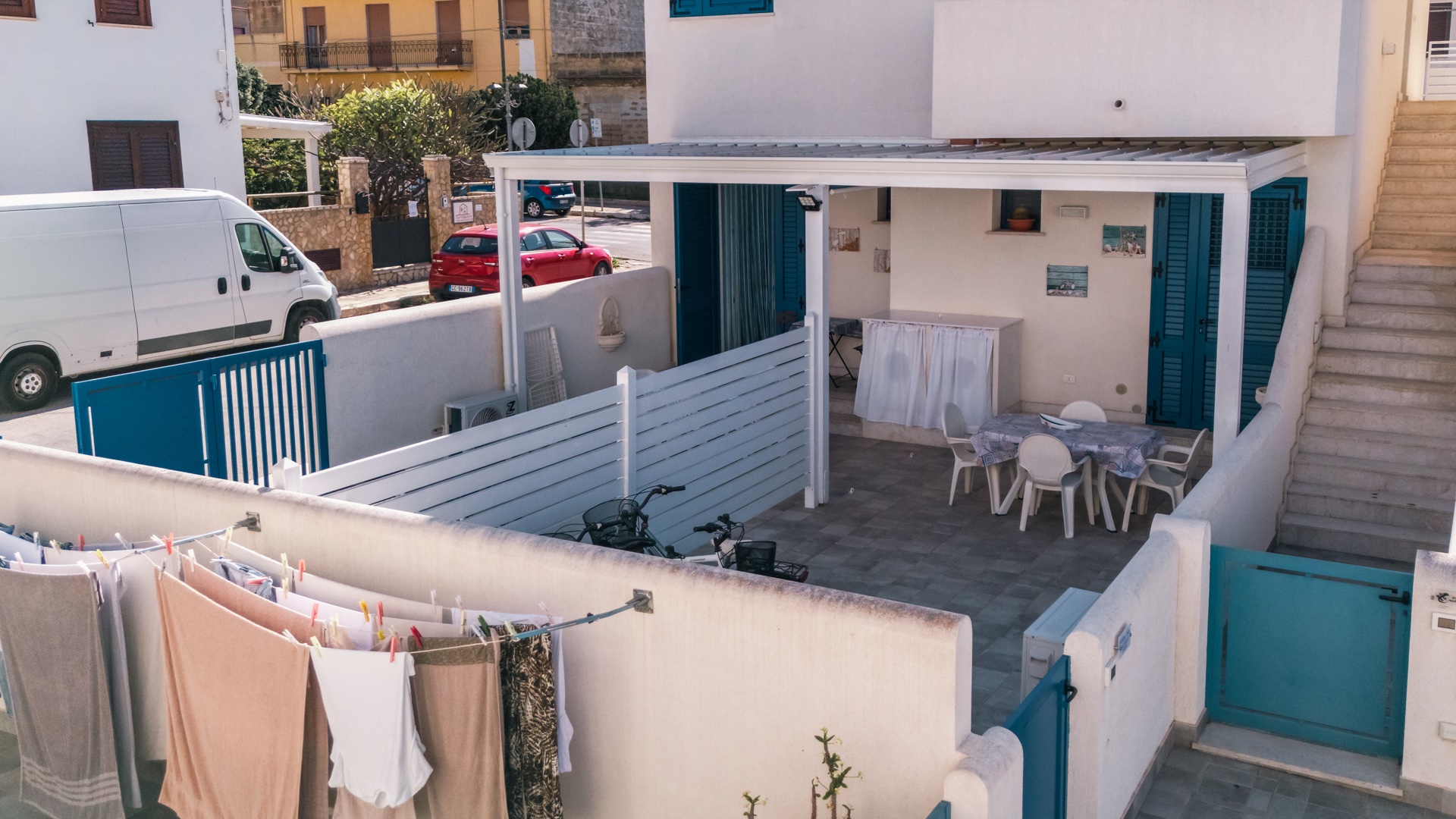 Vista obliqua della veranda e del cortile di Holiday Asia con bici e cancelli azzurri